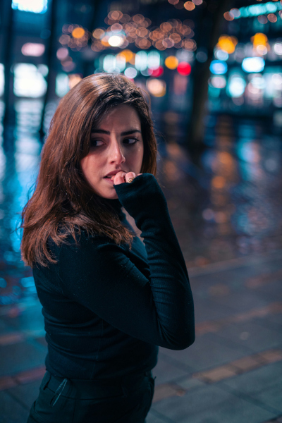 une jeune femme dans la rue inquiète regarde derrière elle